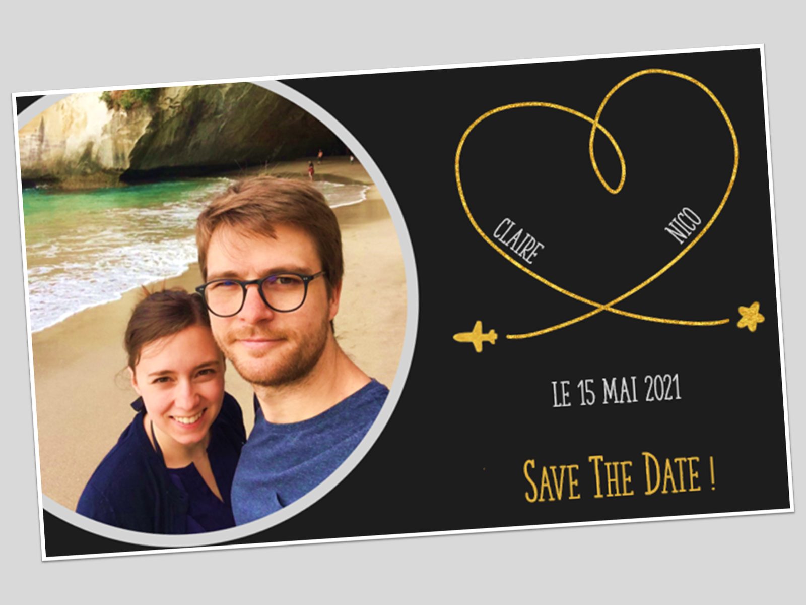 “Save The Date!” card from Claire and Nico for May 15, 2021, with their selfie on a beach and a golden heart traced by a small plane